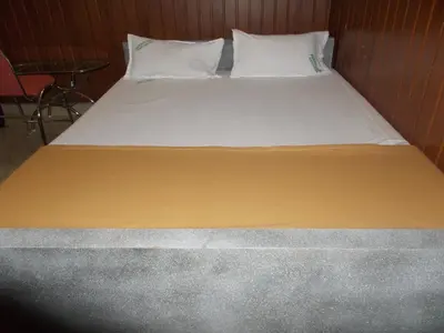 a large bed with yellow sheets and white pillows at Avanti Inn in Guruvāyūr