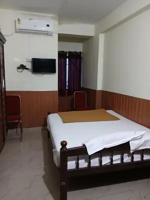a bedroom with a bed and a tv on the wall at Avanti Inn in Guruvāyūr