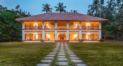 a large house with a lawn in front of it at Windermere River House in Neriyamangalam