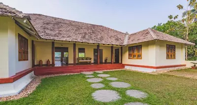 a house with a lawn in front of it at Windermere River House in Neriyamangalam