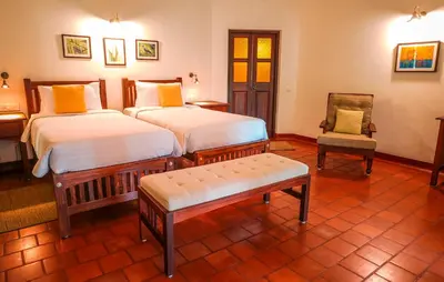 a hotel room with two beds and a chair at Windermere River House in Neriyamangalam