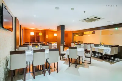 a dining room with white tables and chairs at JK Residency Kelakam in Kelakam
