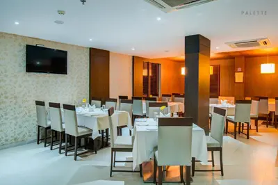 a restaurant with tables and chairs and a flat screen tv at JK Residency Kelakam in Kelakam