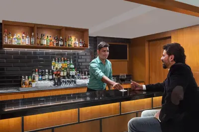 two men sitting at a bar with a bartender at Fairfield by Marriott Coimbatore in Coimbatore
