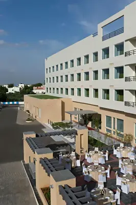 a building with tables and chairs in front of it at Fairfield by Marriott Coimbatore in Coimbatore