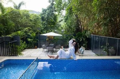 a woman sitting on the edge of a swimming pool at Casa Rio Resorts Athirappilly in Athirappilly