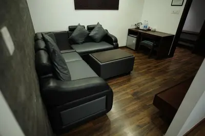 a living room with a black leather couch and a desk at Four N Square Residency in Palakkad