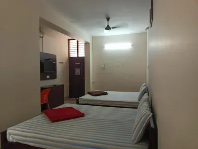 a room with two beds and a television in it at Aditya Residency in Pollāchi