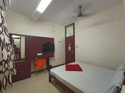 a bedroom with a bed and a desk and a chair at Aditya Residency in Pollāchi