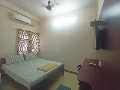 a small room with a bed and a television at Aditya Residency in Pollāchi