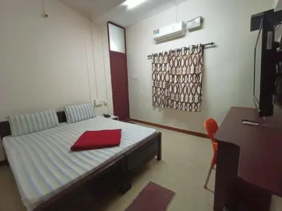 a bedroom with a bed with a red towel on it at Aditya Residency in Pollāchi