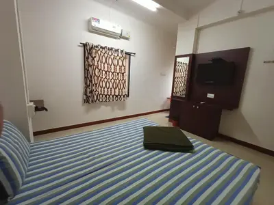 a bedroom with a bed and a television in it at Aditya Residency in Pollāchi