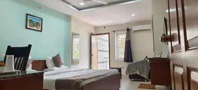 a bedroom with a bed and a dresser and windows at Sugamya Corner Guesthouse in Mysore