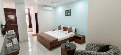 a hotel room with a bed and a chair at Sugamya Corner Guesthouse in Mysore