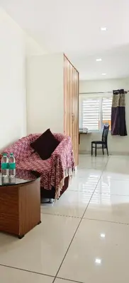 a bedroom with a bed and a table in a room at Sugamya Corner Guesthouse in Mysore