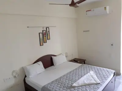a bedroom with a white bed and a ceiling fan at Hotel Paradise Inn in Tiruppūr