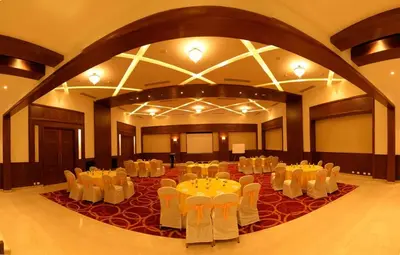 a banquet hall with white tables and white chairs at Lemon Tree Hotel Coimbatore in Coimbatore