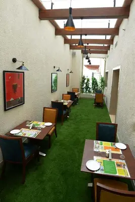 a dining room with tables and chairs and green carpet at Lemon Tree Hotel Coimbatore in Coimbatore