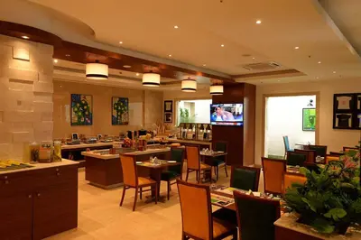a restaurant with tables and chairs and a flat screen tv at Lemon Tree Hotel Coimbatore in Coimbatore