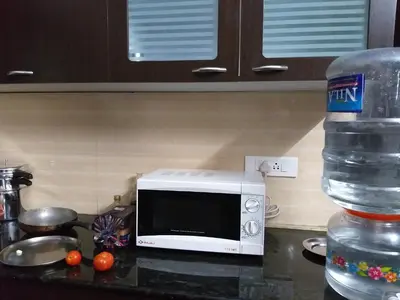 a microwave sitting on a counter next to a water bottle at Holidays and Celebrations in Kodaikānāl