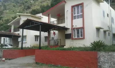 a large white house with a red wall at Holidays and Celebrations in Kodaikānāl