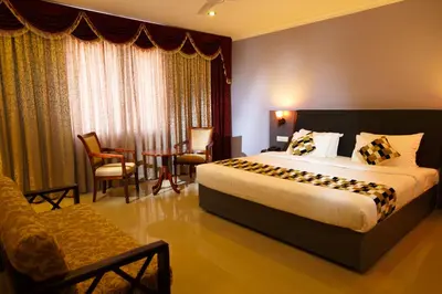 a hotel room with a bed and a table and chairs at Hotel Gopalapuram International in Pollāchi