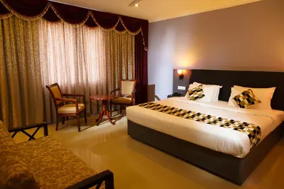 a hotel room with a bed and a table and chairs at Hotel Gopalapuram International in Pollāchi