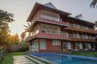 a building with a swimming pool in front of it at Willow Heights in Athirappilly