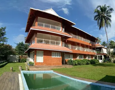 a building with a swimming pool in front of it at Willow Heights in Athirappilly