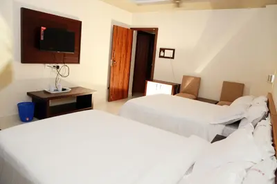 a hotel room with two beds and a flat screen tv at Anandkrishna Residency in Guruvāyūr