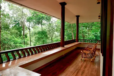 a screened in porch with a view of the forest at Green Garden Wayanad Villas in Vayittiri