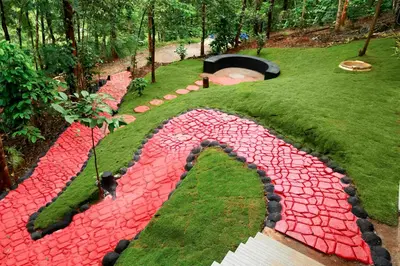 a garden with red rocks in the grass at Green Garden Lotus Villa in Kaniyāmbetta