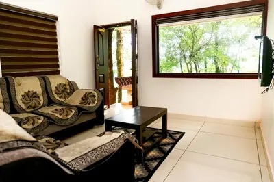 a living room with a couch and a table at Green Garden Lotus Villa in Kaniyāmbetta