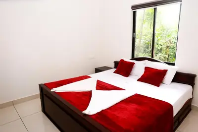 a bedroom with a large white bed with red pillows at Green Garden Lotus Villa in Kaniyāmbetta