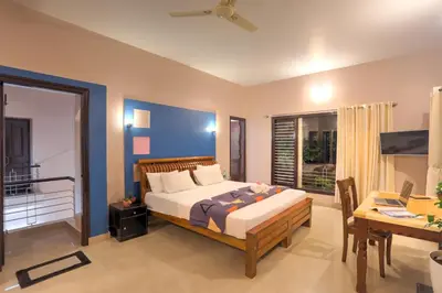 a bedroom with a bed and a table and a desk at Royal Woods Coorg in Madikeri