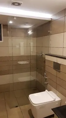 a bathroom with a toilet and a glass shower at U C plaza in Perintalmanna