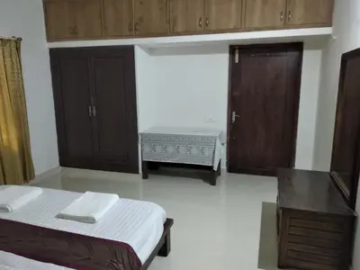 a room with two beds and a bench and cabinets at Kwality Estate in Madikeri