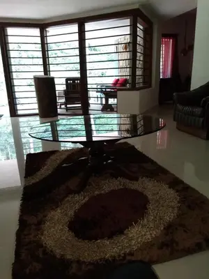a living room with a glass table and a rug at Kwality Estate in Madikeri