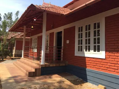 a red brick house with a porch and a balcony at Marsim Holiday Resort in Vythiri