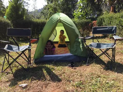 two children playing in a green tent with two chairs at Marsim Holiday Resort in Vythiri