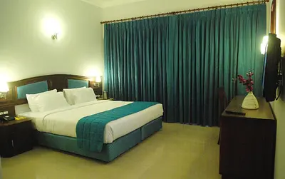 a hotel room with a bed and green curtains at Hotel Elite Palazzo in Kāladi