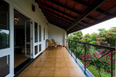 a balcony with chairs and tables on a house at After the Rains - Rainforest Lodge in Meppādi