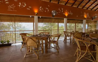 a restaurant with wooden tables and chairs and windows at After the Rains - Rainforest Lodge in Meppādi