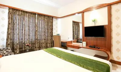 a hotel room with a bed and a desk and a television at Treebo Premium Akshaya Mahal Inn in Mysore