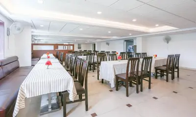 a dining room with long tables and chairs in it at Treebo Premium Akshaya Mahal Inn in Mysore
