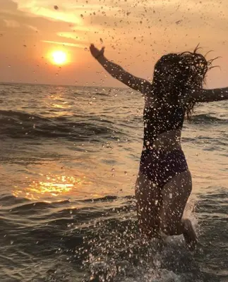 a woman running in the water in the ocean at Lakefront Beach Homes in Cherai Beach
