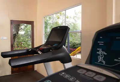 a treadmill with a mirror in a room with a window at Fortune Resort Sullivan Court, Ooty - Member ITC Hotels' Group in Ooty