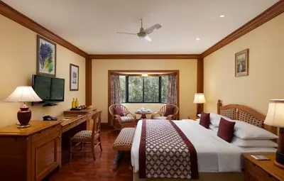 a hotel room with a bed and a desk and a television at Fortune Resort Sullivan Court, Ooty - Member ITC Hotels' Group in Ooty