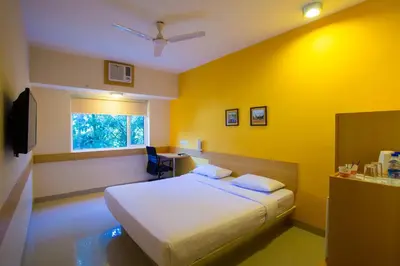 a bedroom with a bed and a yellow wall at Ginger Mysore in Mysore