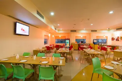 a restaurant with tables and chairs and a flat screen tv at Ginger Mysore in Mysore